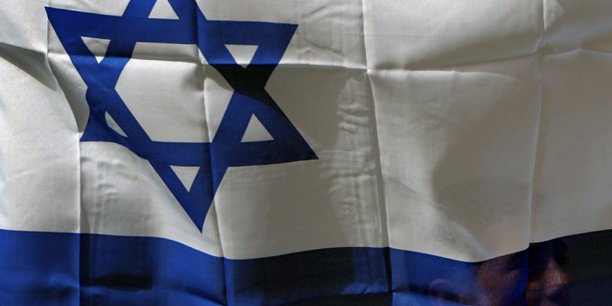 Un israelien tient le drapeau d'israel dans la ville de shfaram[reuters.com]