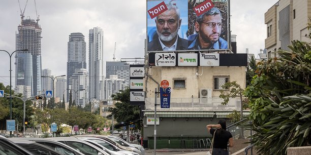 Une femme marche près d’un panneau affichant les portraits des leaders du Hamas avec le slogan « assassinés », à Tel Aviv, vendredi.