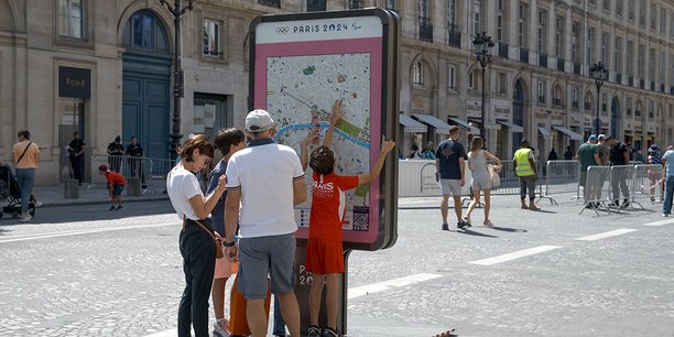 Touristes en train de regarder un plan de Paris lors des JO 2024.