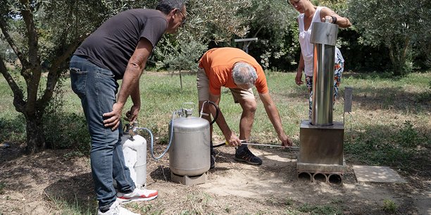 Frédéric Jouffret (au centre) effectue une démonstration du générateur pour l'ensemencement des nuages dans le jardin de Jean-Claude Micol (à gauche) en présence de Sandra Scavennec de Previgrêle, à Carpentras, juillet 2024.