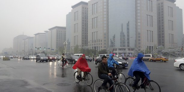 Residents ride their bicycles next to vehicles traveling along the chang'an avenue amid rainfalls on a hazy day in central beijing[reuters.com]