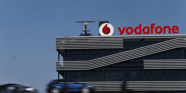 A truck carrying cars speeds past the headquarters of vodafone in madrid[reuters.com]