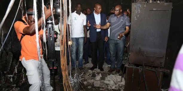 Le ministre ivoirien de la Communication et de l’économie numérique, Bruno Kone (en costume), constant les dégâts causés par l'incendie qui a ravagé le centre technique du groupe Orange, le 1er mai 2018 à Abidjan.