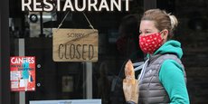 Une femme portant un masque passe devant un restaurant fermé à cause de l'épidémie de coronavirus, le 16 avril 2020 à Cannes.