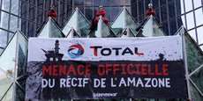 Le 27 mars 2017, des militants de Greenpeace accrochent une banderole qui dit Total, menace officielle du récif amazonien lors d'une manifestation devant le siège du géant pétrolier français Total à La Défense, près de Paris.