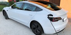 Un véhicule Tesla Model 3 est en train de recharger sa batterie sur une prise de charge à domicile.