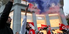 Des personnes tiennent des drapeaux du syndicat espagnol CGT lors d'une manifestation devant un magasin de vêtements Zara à Madrid