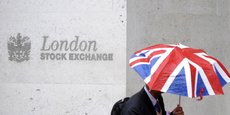 Un travailleur s'abrite de la pluie alors qu'il passe devant la Bourse de Londres