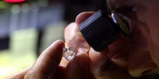 Un employé examine un diamant brut à l'usine Flanders Manufacturing