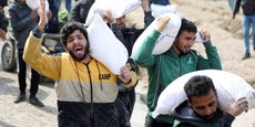 Des Palestiniens transportent des sacs de farine récupérés dans un camion humanitaire à Gaza