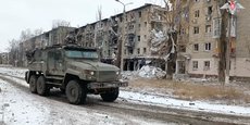 Un véhicule militaire russe passe devant des bâtiments résidentiels endommagés dans la ville d'Avdiivka