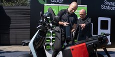 À gauche, Dara Khosrowshahi, PDG d’Uber, examine une moto électrique.