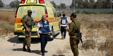 Des soldats israéliens et des médecins marchent près d'une ambulance après que le groupe islamiste palestinien Hamas a revendiqué une attaque au point de passage de Karem Shalom, près de la frontière israélienne avec Gaza