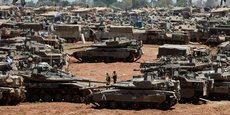 Des soldats israéliens passent devant des véhicules militaires près de la frontière entre Israël et la bande de Gaza