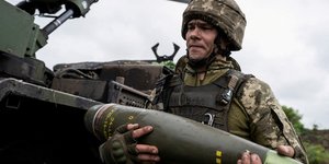 Un militaire ukrainien porte un obus pour un obusier automoteur caesar avant de tirer en direction des troupes russes pres d'avdiivka