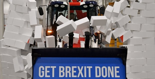 En pleine campagne pour les législatives, Boris Johnson fonce, au volant d'un bulldozer aux couleurs britanniques, vers un mur en briques de polystyrène sur lequel on peut lire le mot impasse.