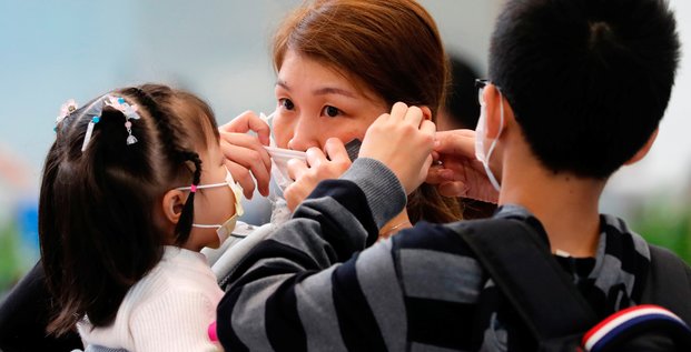Femme ajuste masque pour prévenir déclenchement nouveau coronavirus Chine
