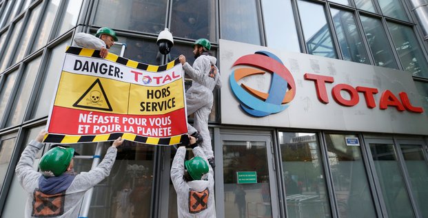 Des militants d'Attac accrochent une bannière à la façade de l'immeuble Total