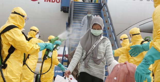 Coronavirus / Covid-19 : Des médecins diffusent un spray antiseptique sur une femme rapatriée de Chine en Indonésie, le 2 février 2020