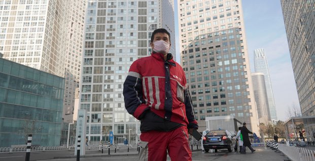 Coronavirus / Covid-19 : un livreur KFC marche dans un complexe commercial situé dans le quartier des affaires de Beijing en Chine