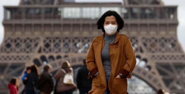 Coronavirus/Covid-19 : Une femme portant un masque marche sur l'esplanade du Trocadéro, devant la Tour Eiffel