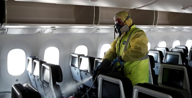 Air France présente les nouvelles mesures de sécurité sanitaire pour éviter la propagation du coronavirus. Ici, un homme diffuse du désinfectant à l'intérieur d'un Boeing 787