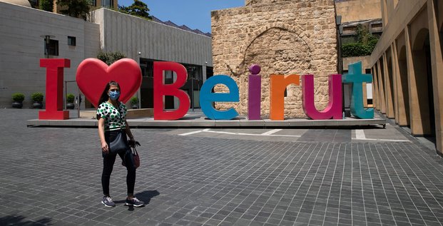 Liban : une femme portant un masque passe devant un signe j'aime Beyrouth alors que les autorités ont imposé un nouveau confinement de deux semaines pour limiter la propagation du coronavirus