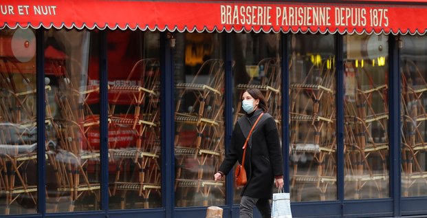 France / coronavirus / confinement : une femme portant un masque passe devant un restaurant fermé à Paris le 25 novembre 2020