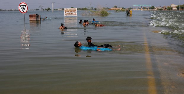 Des garcons jouent dans les eaux de crue sur l'autoroute principale de l'indus, suite aux inondations a sehwan, au pakistan