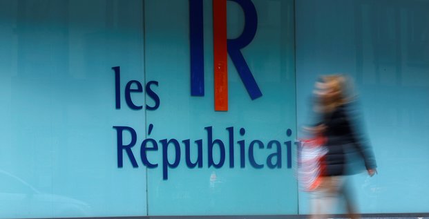 Une femme passe devant un logo du parti francais les republicains (lr) a paris, france