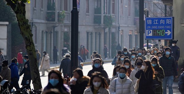 Des personnes portant des masques de protection marchent dans une rue a shanghai, en chine