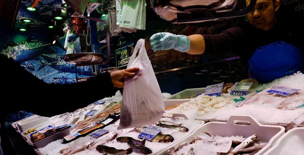 Un poissonnier tend un sac de poisson a un client dans un supermarche alors que le gouvernement espagnol annonce des mesures pour lutter contre l'inflation, a madrid.