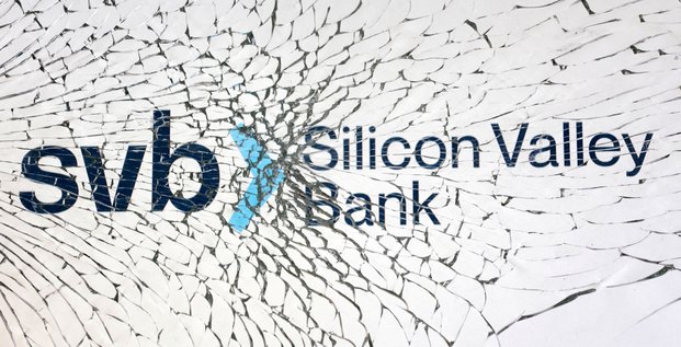 Photo d'illustration du logo de la svb (silicon valley bank) derriere une vitre brisee