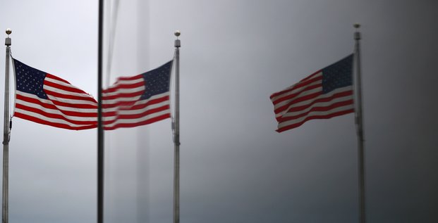 Le capitole des etats-unis et les drapeaux americains se refletent dans une fenetre a washington