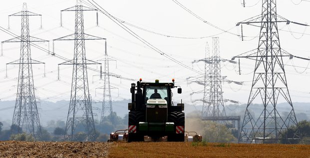 Un agriculteur travaille dans un champ entoure de pylones electriques a ratcliffe-on-soar, en angleterre