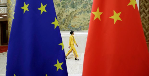 Photo d'archives: une femme passe devant les drapeaux de l'ue et de la chine avant le dialogue economique de haut niveau entre l'ue et la chine a pekin