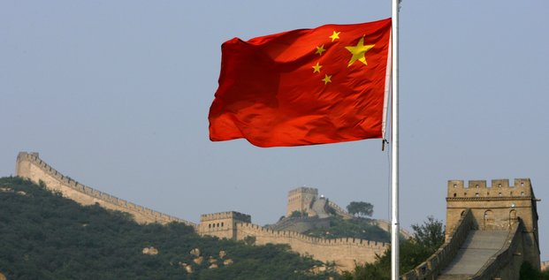 Un drapeau chinois flotte devant la grande muraille de chine, situee au nord de pekin