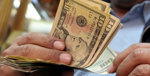 Un homme compte des dollars americains dans un bureau de change