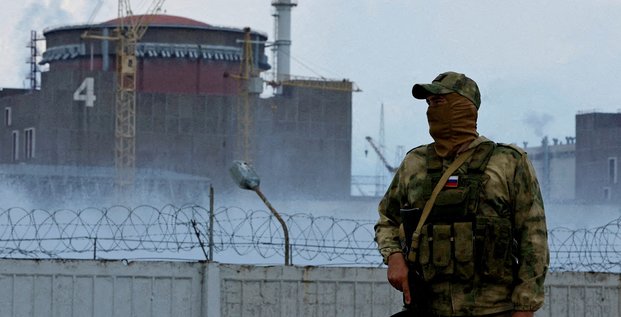 Un militaire avec un drapeau russe sur son uniforme monte la garde pres de la centrale nucleaire de zaporijjia
