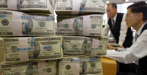 Des employés d'une banque travaillent près d'une pile de billets de monnaie américaine (le dollar) / Argent