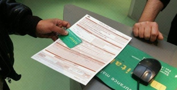 Une personne présente sa carte vitale et une feuille de soins dans une antenne de la Caisse d'assurance maladie, à Paris