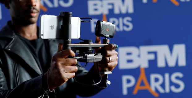 Un journaliste de BFM Paris tient un iPhone pour filmer lors d'une conférence de presse en octobre