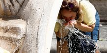 Une personne se rafraichit a la fontana della barcaccia pendant une canicule a rome