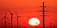Des eoliens et des pylones electriques sont photographies au lever du soleil