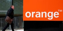 Un homme passe devant le logo de french orange pres de paris