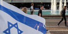 Des personnes passent devant un drapeau israelien a tel aviv